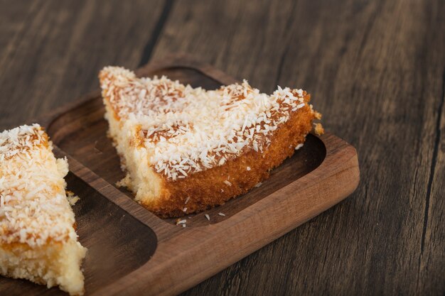 Fatias de bolo de sobremesa com lascas de coco colocadas sobre uma mesa de madeira.