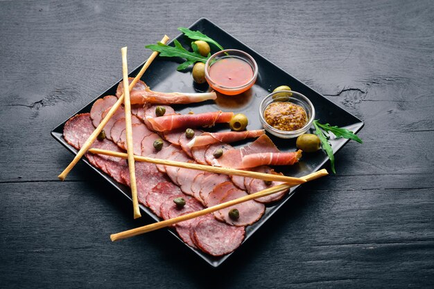 Fatias de carne em um prato com ketchup e mostarda. Salsicha e bacon. Em um fundo de madeira. Vista do topo. Espaço livre.