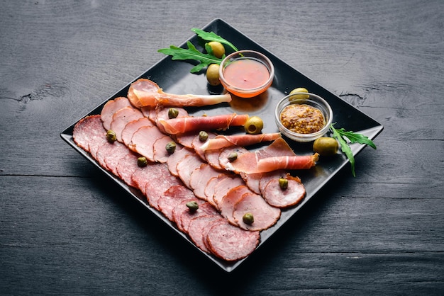 Fatias de carne em um prato com ketchup e mostarda. Salsicha e bacon. Em um fundo de madeira. Vista do topo. Espaço livre.