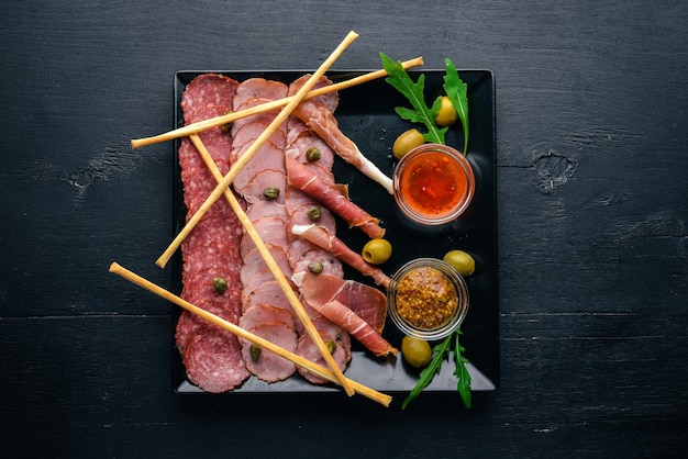 Fatias de carne em um prato com ketchup e mostarda Salsicha e bacon Em um fundo de madeira Vista superior Espaço livre