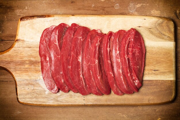 Fatias de carne em uma placa de cozinha de madeira em uma vista superior