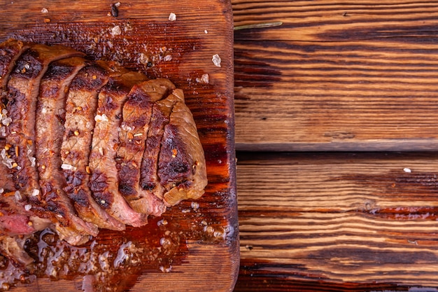 Fatias de carne grelhada bife Ribeye com especiarias na tábua de madeira rústica