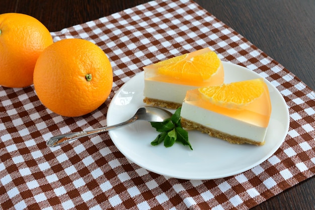 fatias de cheesecake de laranja em pires branco com colher de chá na toalha de mesa marrom