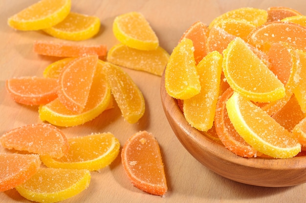 Foto fatias de doce de laranja e limão em uma tigela de madeira