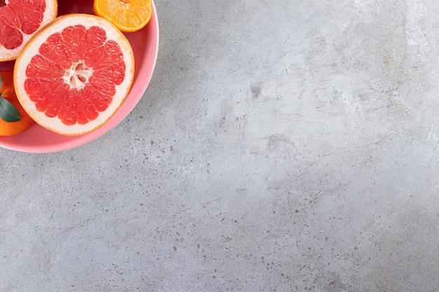 Fatias de frutas cítricas de laranja e toranja colocadas em uma tigela rosa