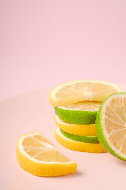 Fatias de frutas cítricas saborosas frescas de limão e limão empilhadas no prato rosa
