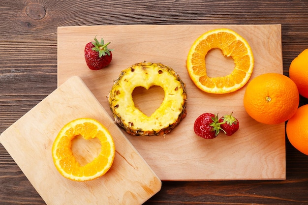 Fatias de frutas com corte em forma de coração e bagas na mesa close-up