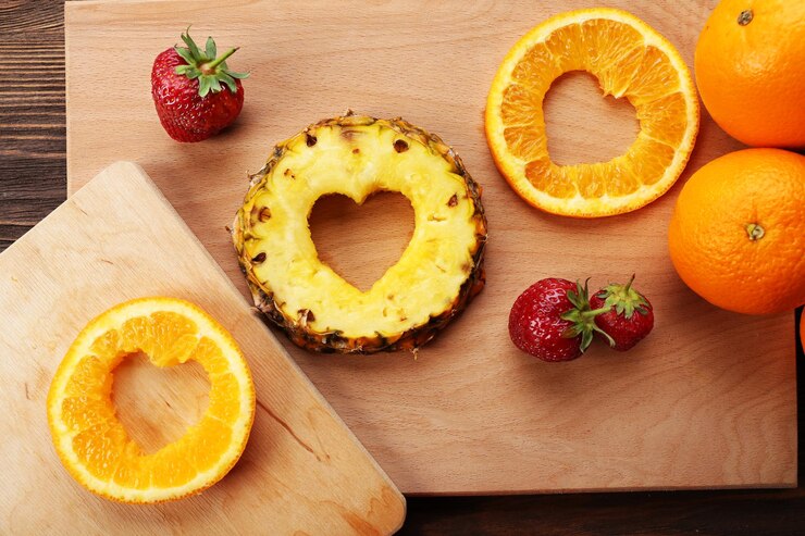 Foto fatias de frutas com corte em forma de coração e bagas na mesa close-up
