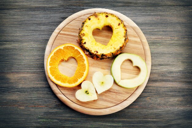 Fatias de frutas com corte em forma de coração em fundo de madeira