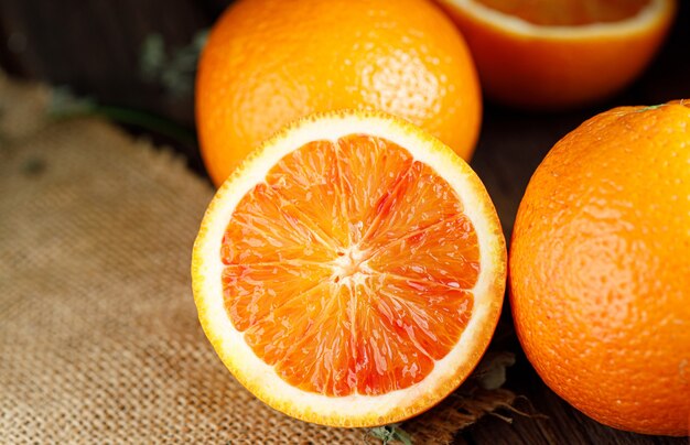 Fatias de frutas de laranjas sangue sicilianas sobre fundo de madeira escuro antigo.