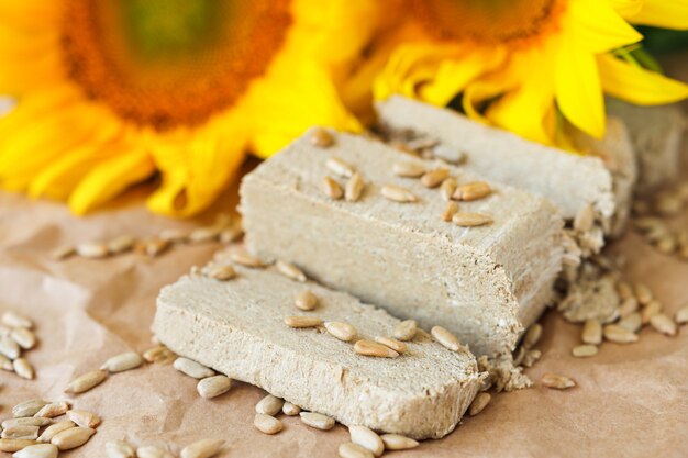 Fatias de halva e sementes de girassol, vista de cima, comida doce tradicional com flores amarelas