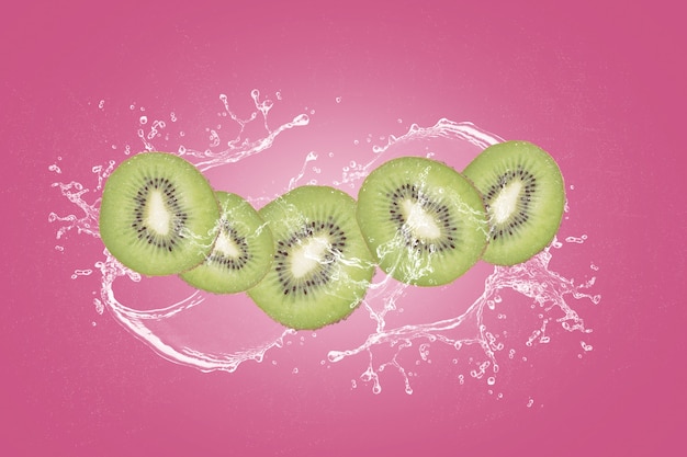 Fatias de kiwi com respingos de água isolados no blackground rosa.