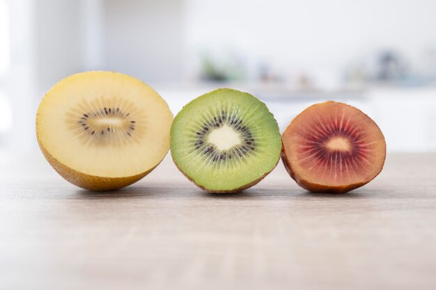 Foto fatias de kiwi verde amarelo e vermelho em um fundo de mesa