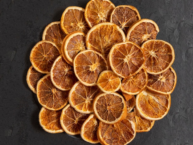 Foto fatias de laranja desidratada em pedra preta. foco seletivo.