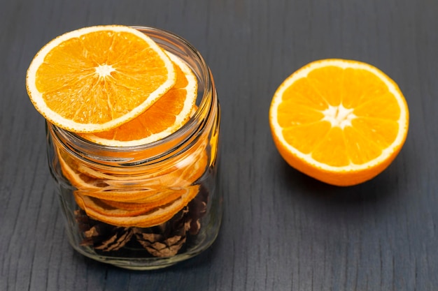 Fatias de laranja secas e cones de abeto em frasco de vidro Laranja fresca na mesa Decorações de Natal