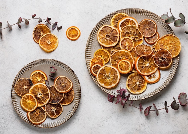 Fatias de laranja secas em pratos de cerâmica com ingredientes de ramos de eucalipto para cozinhar ou para o natal