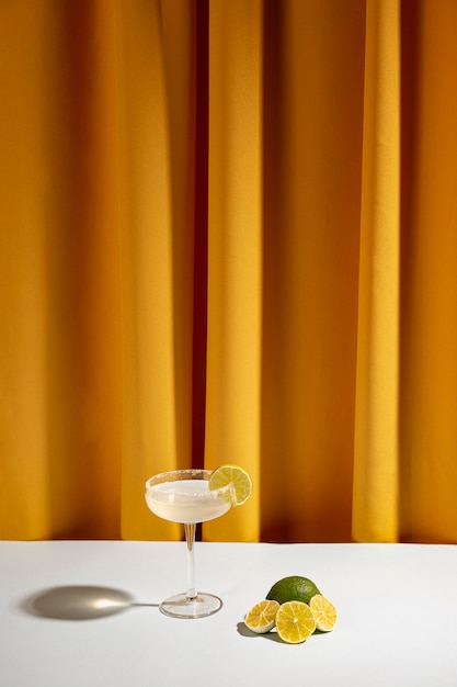 Foto fatias de limão cortados ao meio perto do coquetel na mesa contra a cortina