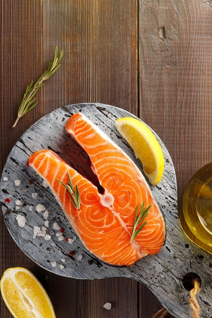 Fatias de limão de bife de peixe vermelho e especiarias em uma placa de madeira