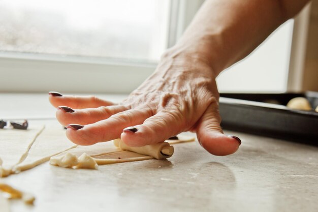 Foto fatias de massa crua misturada com bagas deitam-se na bandeja de cozimento cozinhando prato de cozimento as mãos das mulheres rolam a massa em um bagel