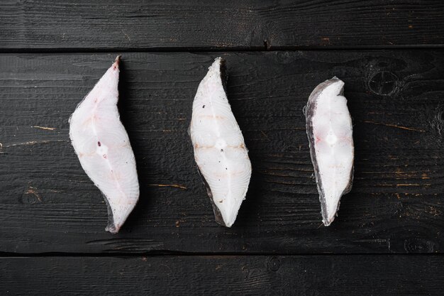 Fatias de mercado de frutos do mar de peixe branco definido, no fundo preto da mesa de madeira, vista superior plana lay