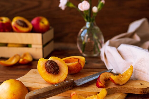 Fatias de nectarina em uma tábua de cortar em uma mesa de madeira. metades e fatias de pêssego doce na cozinha