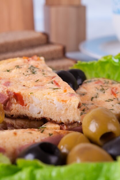 Fatias de omelete em um prato. Contra o fundo de uma toalha de mesa azul