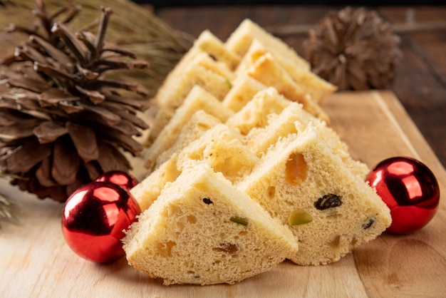 Fatias de panetone em madeira polida, pinhas e bolas de natal em madeira rústica