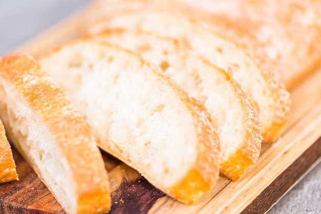 Fatias de pão ciabatta recém-assado na mesa cinza.