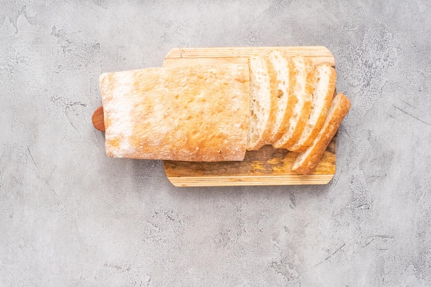 Fatias de pão ciabatta recém-assado na mesa cinza.