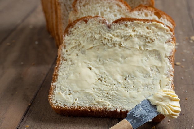 Fatias de pão com margarina em uma mesa de madeira