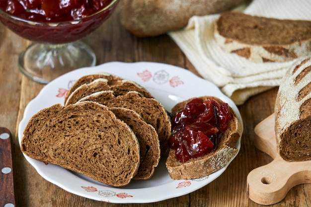 Fatias de pão de centeio com geléia de ameixa em uma mesa de madeira