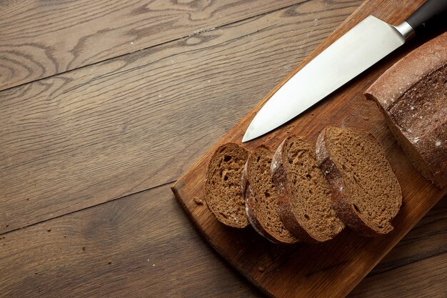fatias de pão de centeio e uma faca close-up, sobre uma tábua de madeira