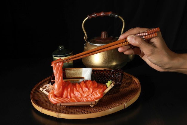 Foto fatias de peixe salmão sashimi no barco com os pauzinhos na mão.