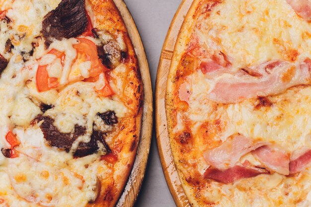 Foto fatias de pizza na bandeja de madeira rústica e fundo escuro.