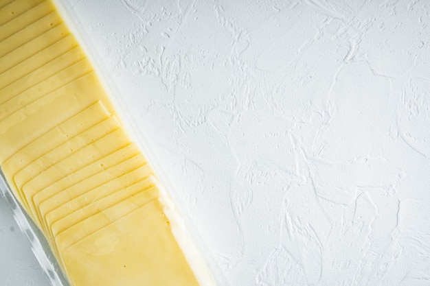 Fatias de queijo amarelo em embalagem lacrada, na mesa branca