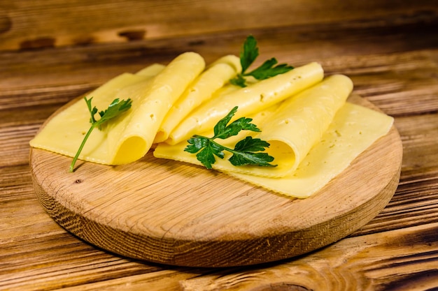 Fatias de queijo e salsa em uma tábua de madeira