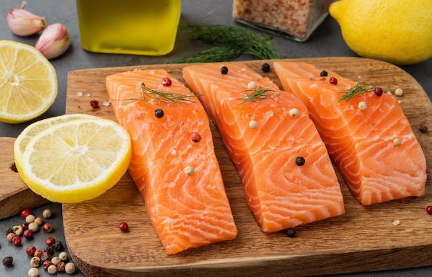 Fatias de salmão cru com temperos sobre placa de madeira