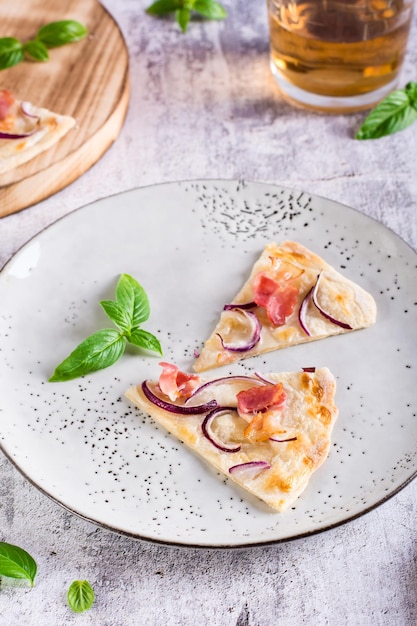 Fatias de tarte flammkuchen francesa com queijo creme de bacon e cebola em um prato vista vertical