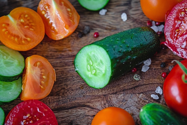 Foto fatias de tomate e pepino em uma tábua de madeira escura