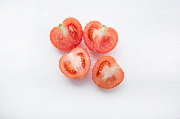 Fatias de tomates frescos em fundo branco de madeira.