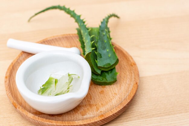 Fatias de uma folha de aloe vera e uma argamassa de cerâmica com gel transparente para fins medicinais da pele