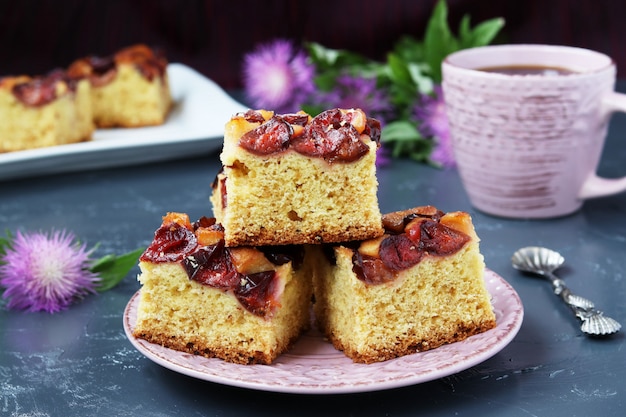 Fatias de uma torta de ameixa em um prato, estão localizadas em um fundo escuro