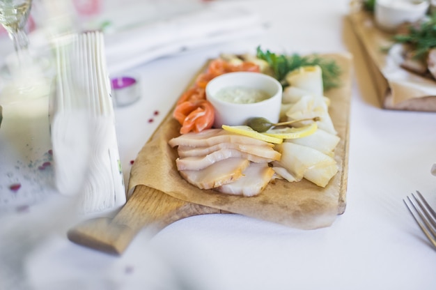 Fatias de vários peixes salgados - salmão, muksun, peixes oleosos na tábua de madeira. Restaurante