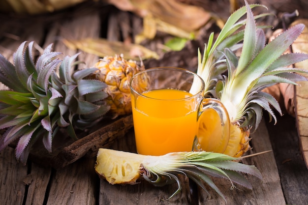 Fatias do abacaxi e asiático-estilo do suco de abacaxi no fundo de madeira velho.