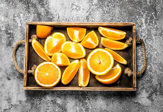 Fatias frescas de laranja em uma bandeja de madeira em um fundo rústico