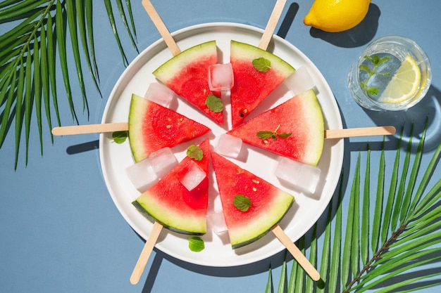 Fatias frescas de picolés de melancia em um prato com cubos de gelo Comida abstrata de verão