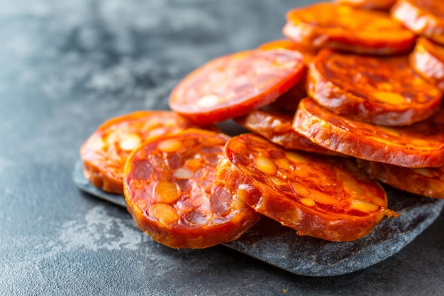 Fatias picantes de chorizo empilhadas em um fundo de textura cinza rico em cores e detalhes