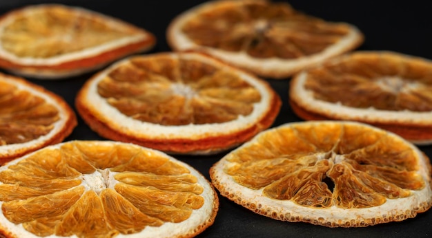 Fatias redondas secas de laranja natural sobre fundo preto como fundo de baixa profundidade de campo