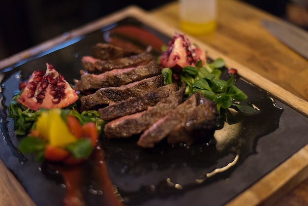 Fatias suculentas de bife grelhado com legumes em uma placa de madeira