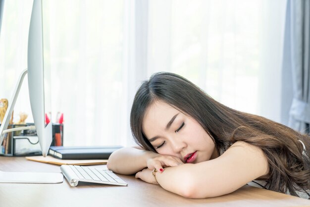 faule asiatische Frau, die im Büro schläft